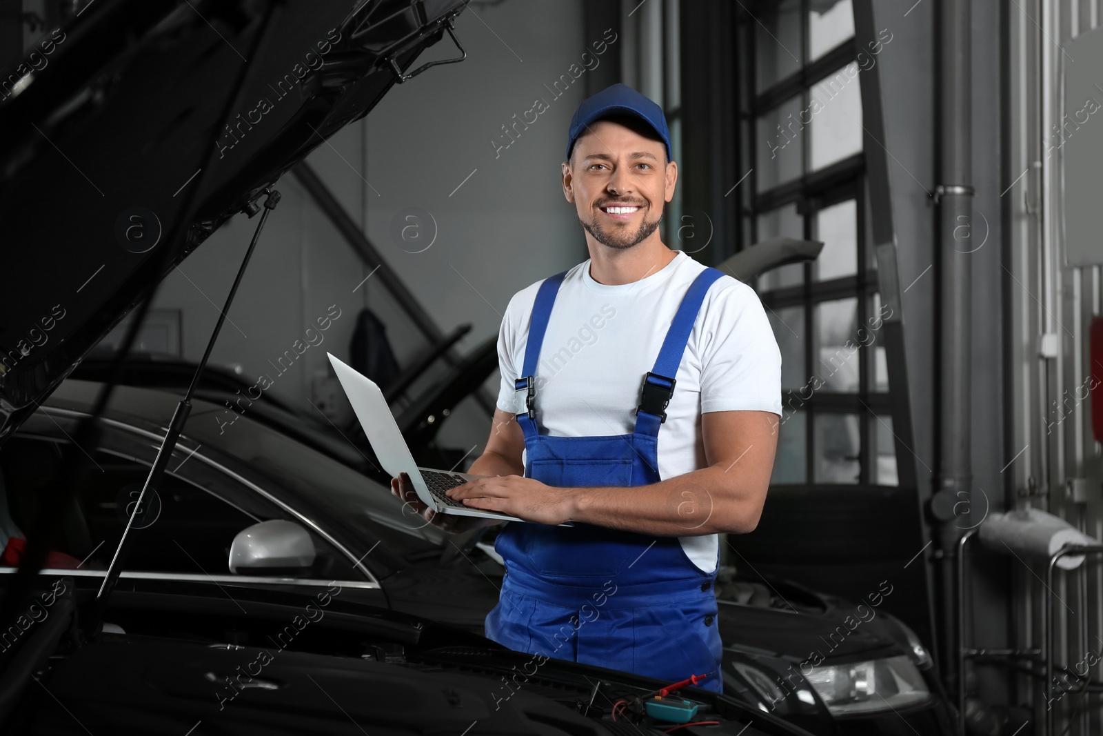 Photo of Mechanic with laptop doing car diagnostic at automobile repair shop