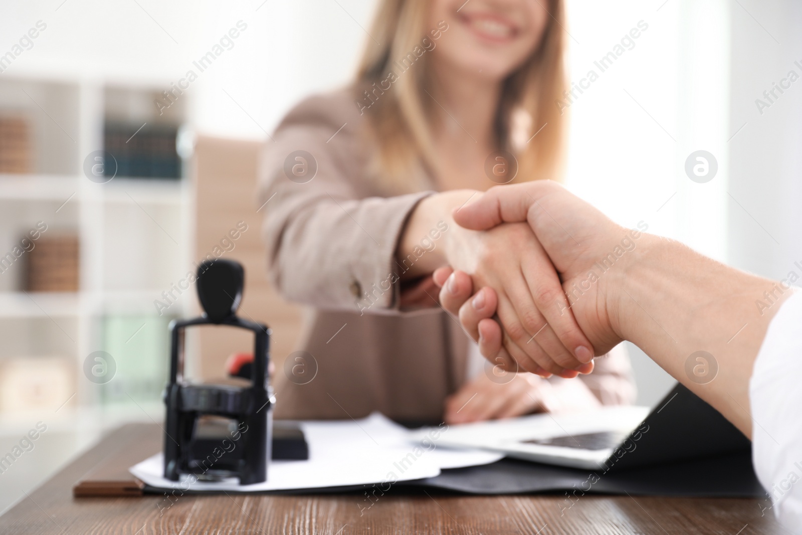 Photo of Business partners shaking hands at table after meeting in office, closeup