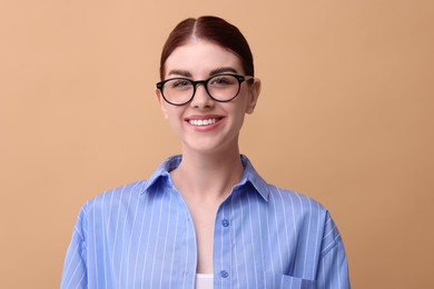 Photo of Portrait of smiling woman in glasses on beige background