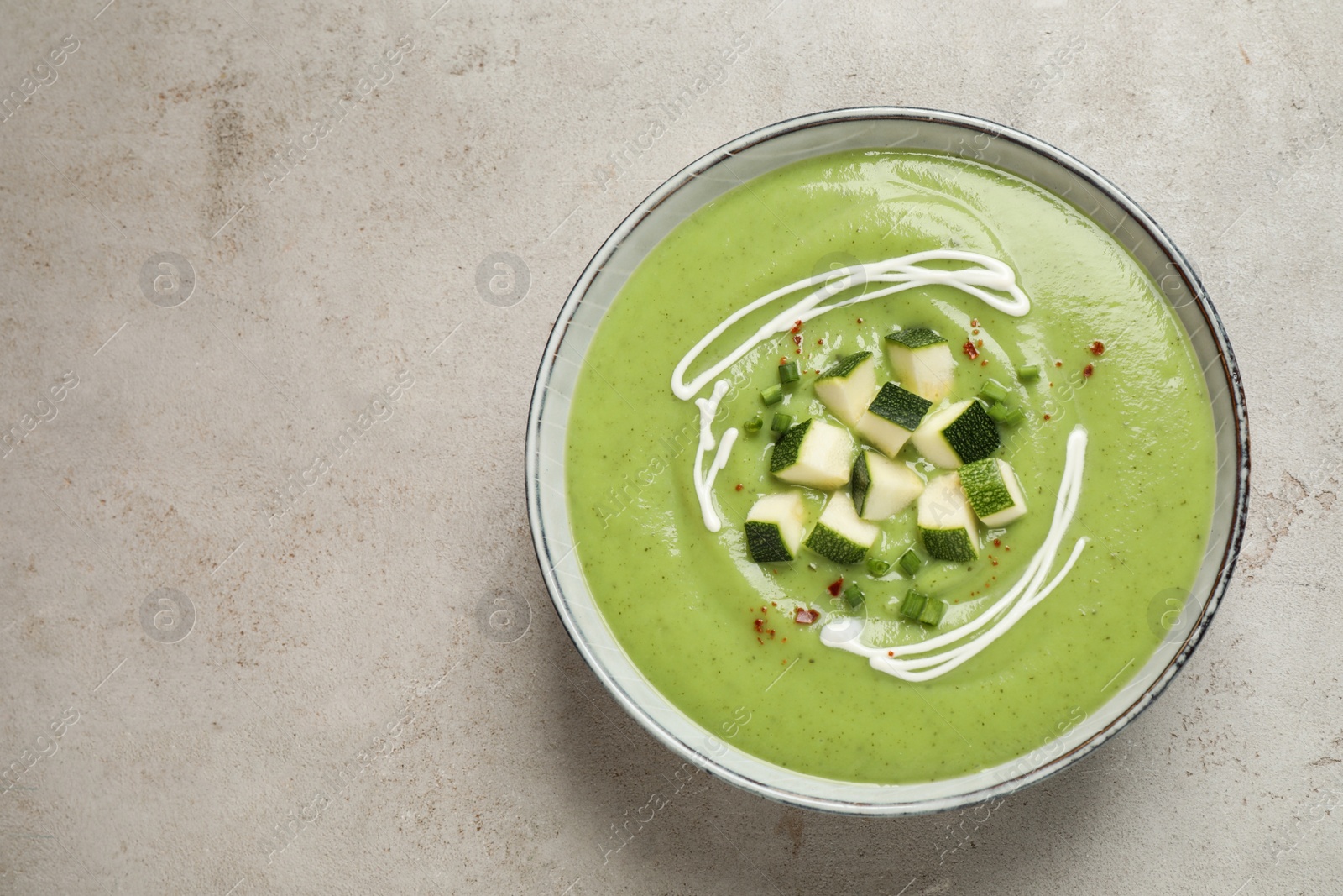 Photo of Tasty homemade zucchini cream soup on light table, top view. Space for text