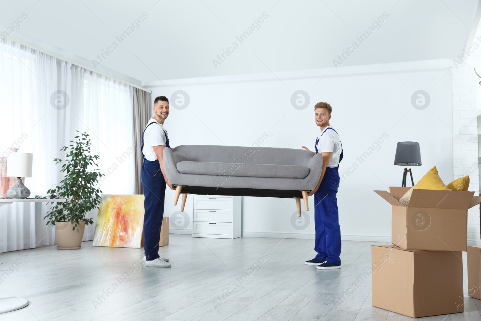 Photo of Moving service employees carrying sofa in room