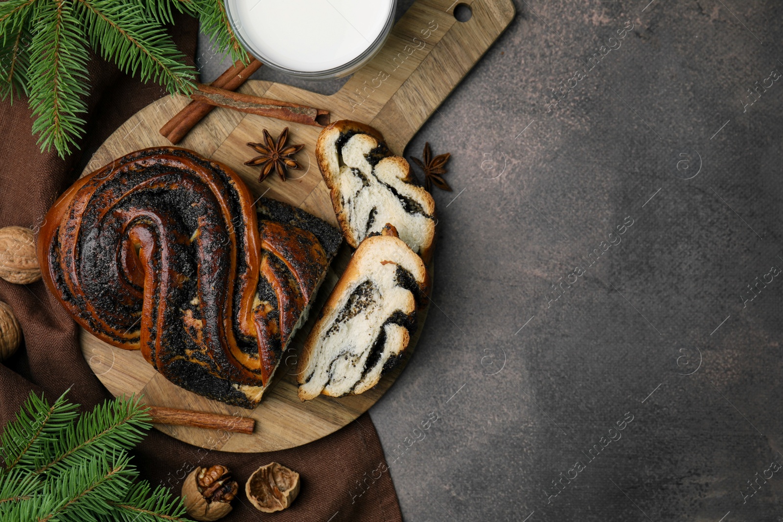 Photo of Flat lay composition with cut poppy seed roll and fir branches on textured table, space for text. Tasty cake