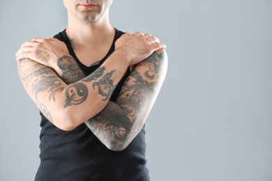 Photo of Young man with stylish tattoos on grey background. Space for text