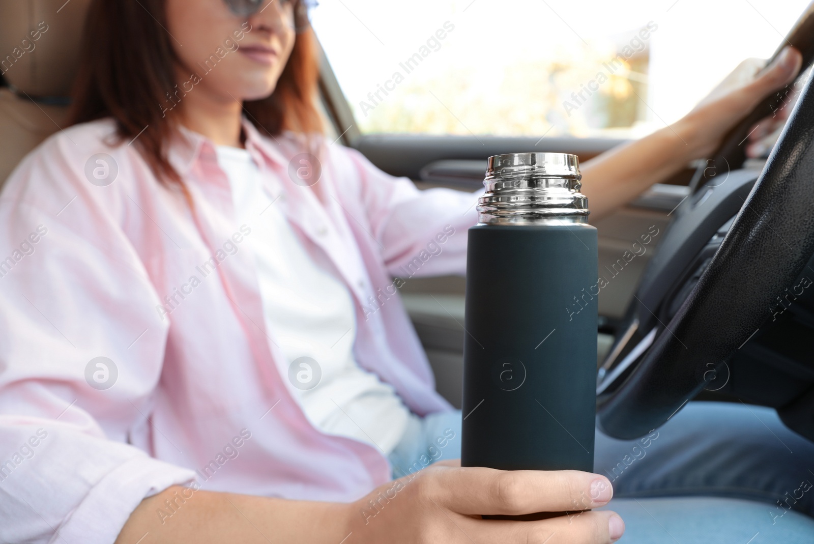 Photo of Woman with thermos driving car, closeup view