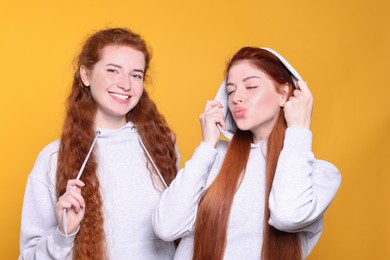 Portrait of beautiful young redhead sisters on orange background