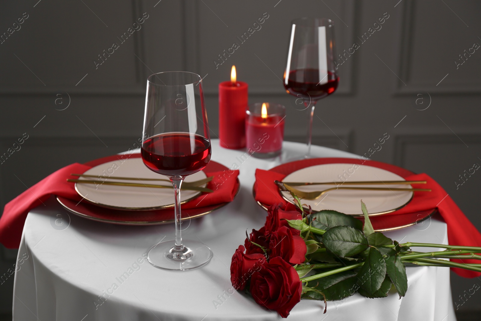Photo of Place setting with roses and candles on white table. Romantic dinner