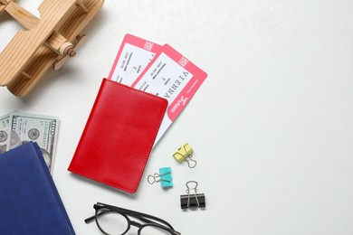 Photo of Flat lay composition with tickets, passport and wooden model of plane on white table, space for text. Business trip