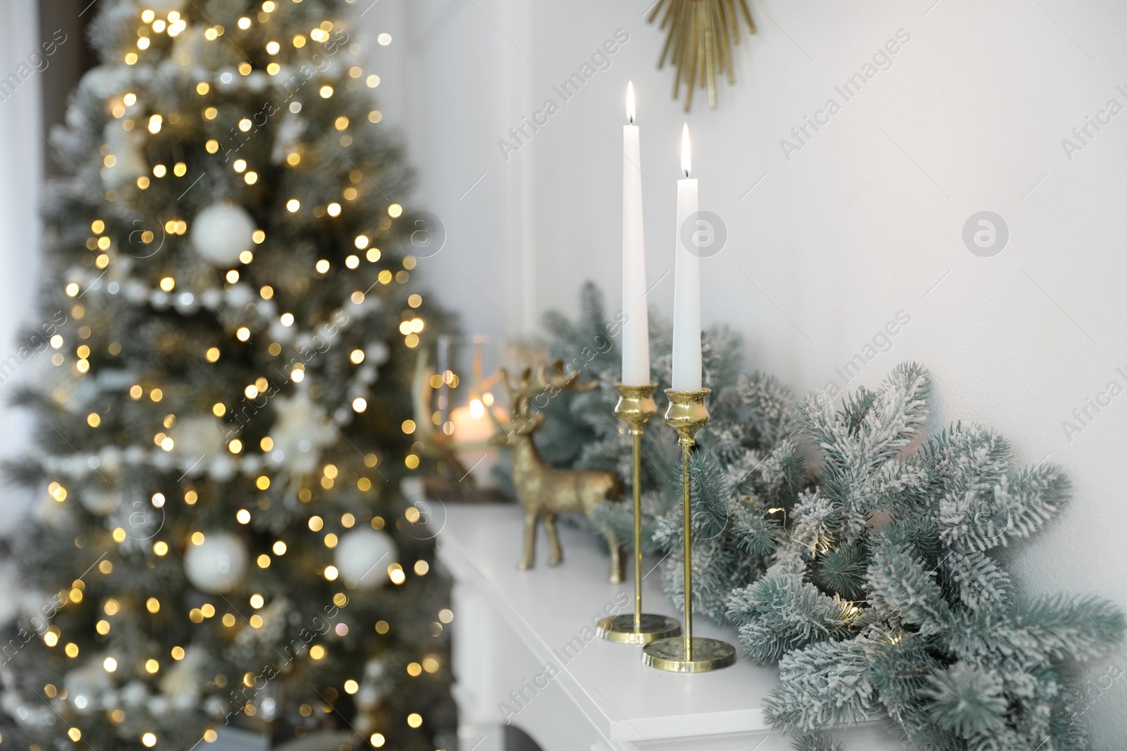 Photo of Burning candles on mantelpiece in decorated room. Christmas celebration