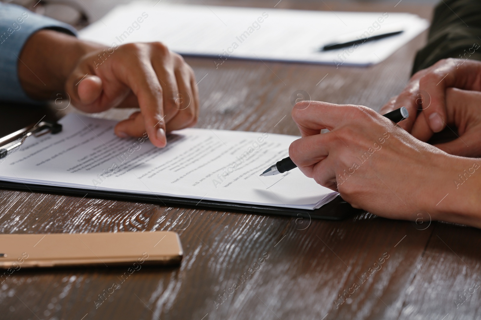 Photo of Notary working with couple at wooden table, closeup