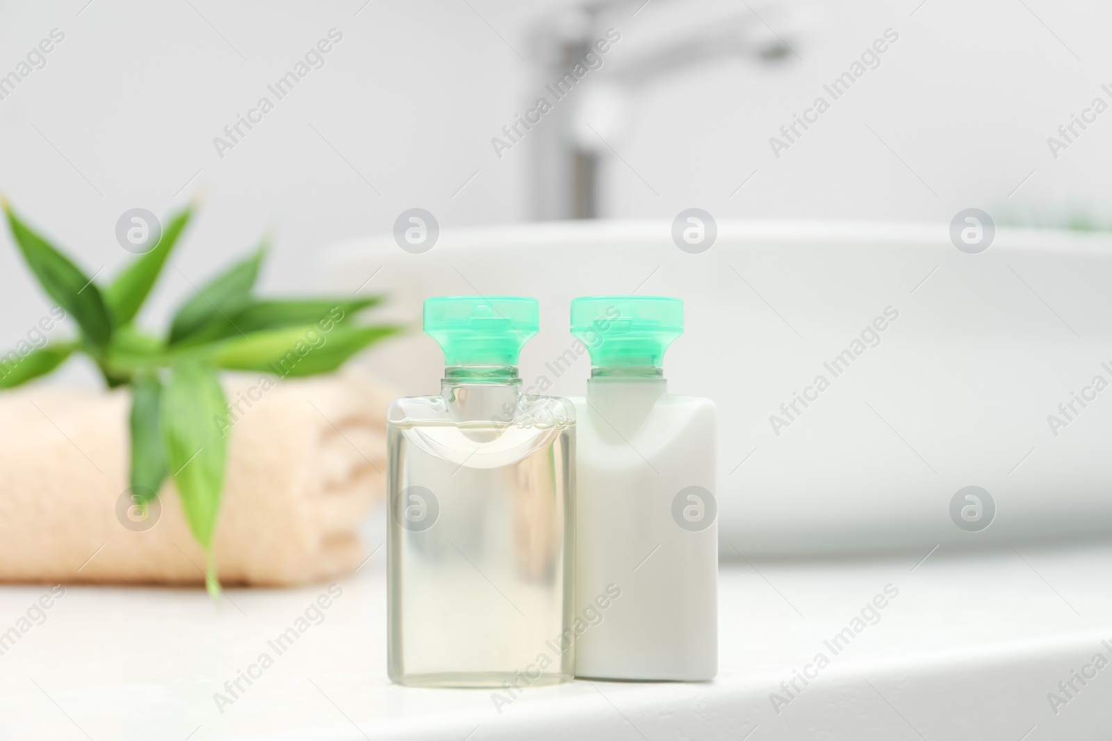 Photo of Mini bottles of cosmetic products on white countertop in bathroom