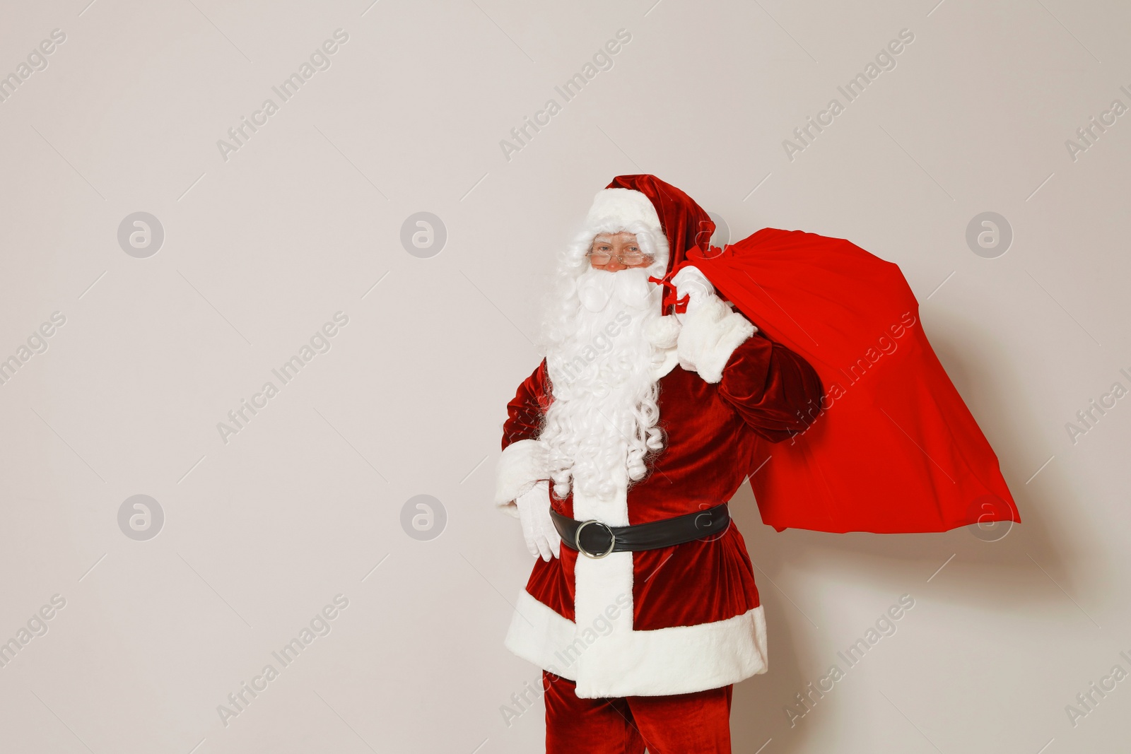 Photo of Authentic Santa Claus with bag full of gifts on grey background. Space for text