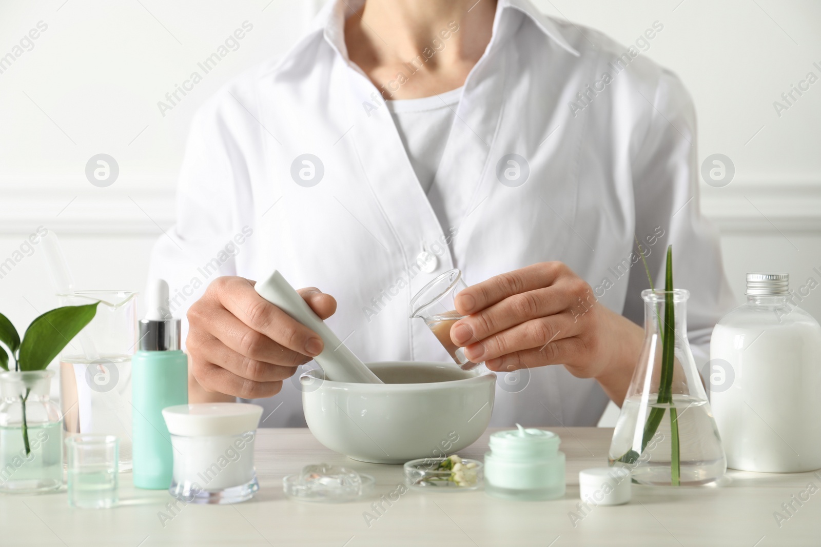 Photo of Scientist making cosmetic product at table in laboratory, closeup