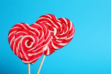Photo of Sweet heart shaped lollipops on light blue background, closeup view with space for text. Valentine's day celebration