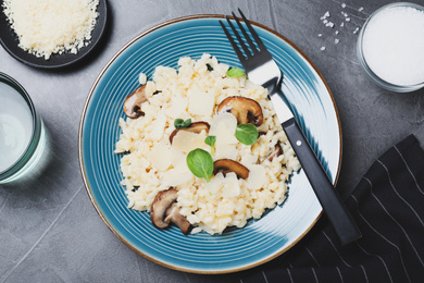 Photo of Delicious risotto with cheese and mushrooms on dark grey table, flat lay
