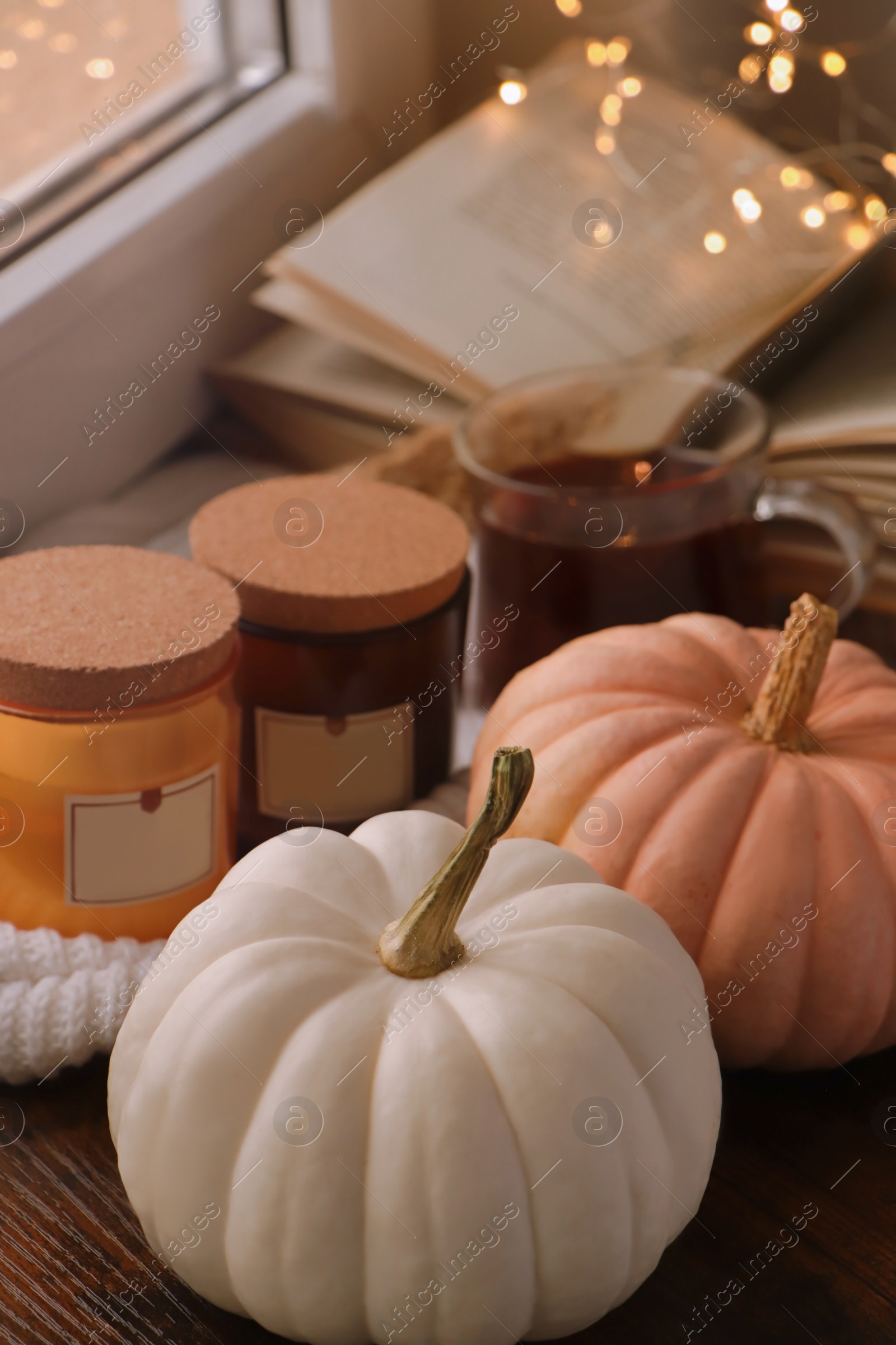 Photo of Beautiful pumpkins and scented candles on window sill indoors