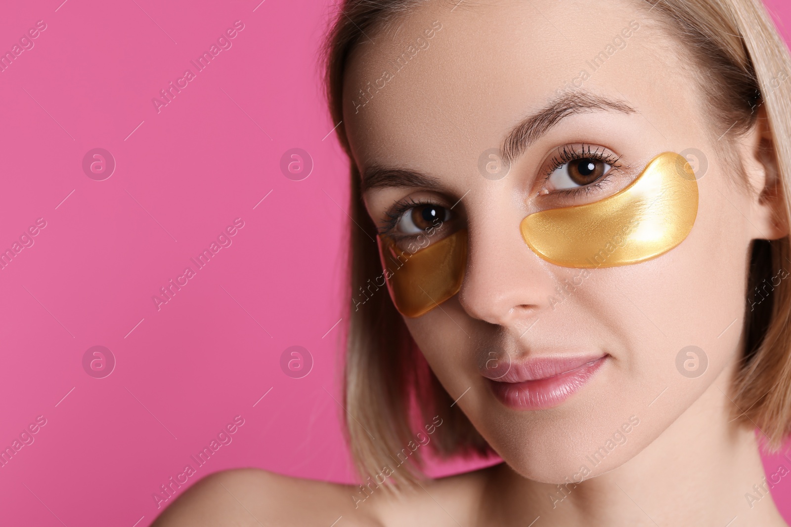 Photo of Beautiful young woman with under eye patches on pink background. Space for text