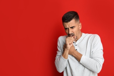 Image of Man coughing on red background, space for text. Cold symptoms