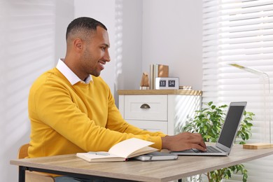 Photo of Young man working on laptop at desk in home office