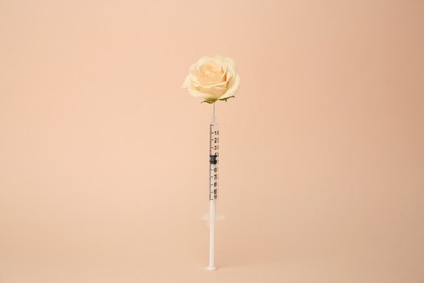 Photo of Medical syringe and rose flower on beige background