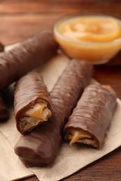 Photo of Sweet tasty chocolate bars with caramel on wooden table, closeup