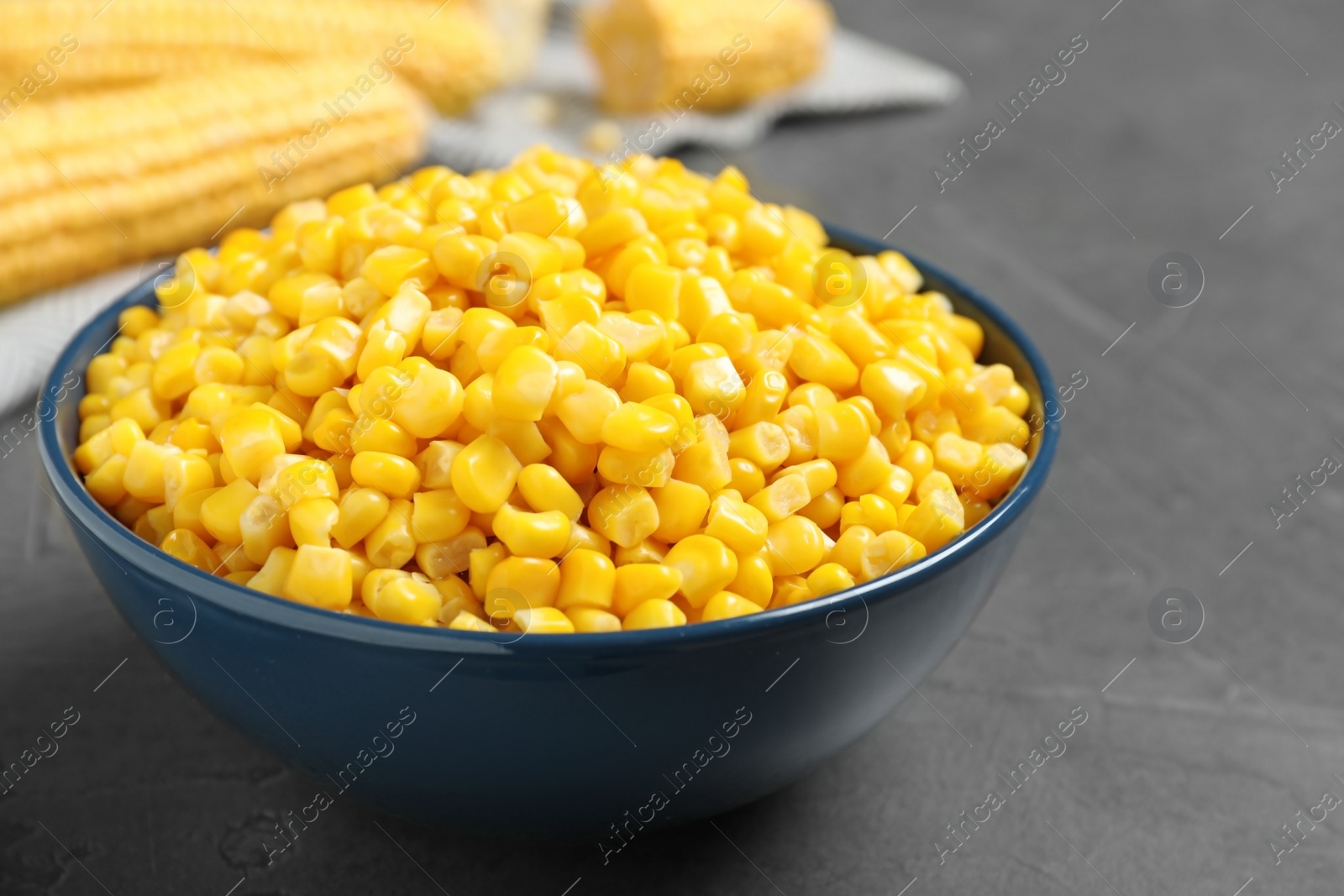 Photo of Delicious canned corn in bowl on grey table, closeup