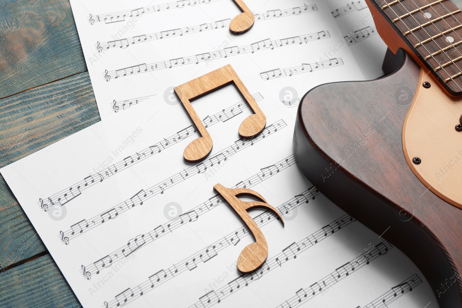 Photo of Guitar and sheets with music notes on wooden table