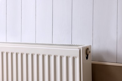 Photo of Modern radiator on white wooden wall. Central heating system