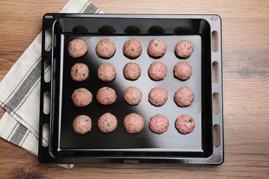 Many fresh raw meatballs on wooden table, top view