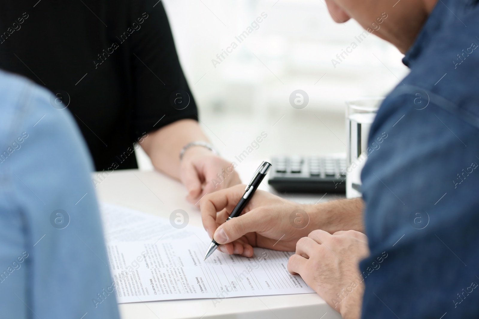 Photo of Young couple discussing pension plan with mature consultant in office