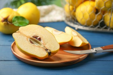 Photo of Tasty ripe quince fruits and knife on blue wooden table, closeup