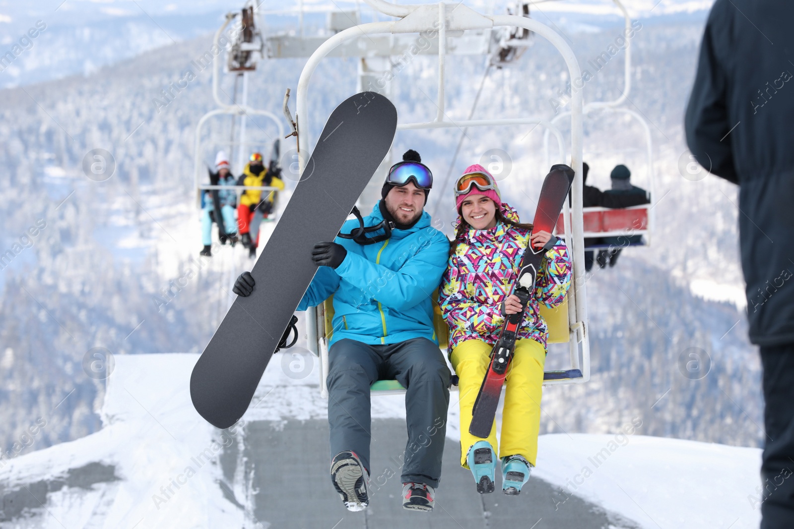 Photo of Couple using chairlift at mountain ski resort. Winter vacation