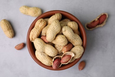 Photo of Fresh unpeeled peanuts in bowl on grey table, top view