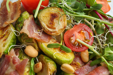 Photo of Delicious roasted Brussels sprouts with bacon on plate, top view