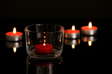 Wax candles burning on table in darkness. Space for text