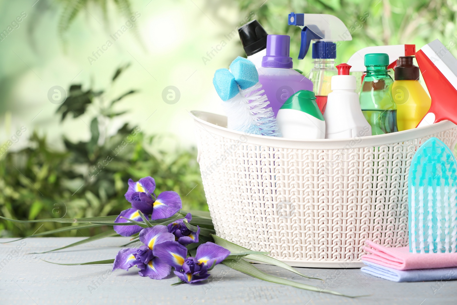 Photo of Spring flowers and cleaning supplies on light wooden table