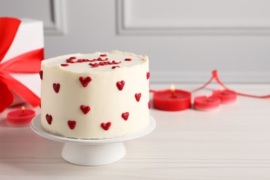 Bento cake, candles and gift box on white wooden table, space for text. St. Valentine's day surprise