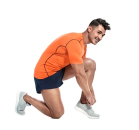 Handsome young runner tying shoelaces on white background