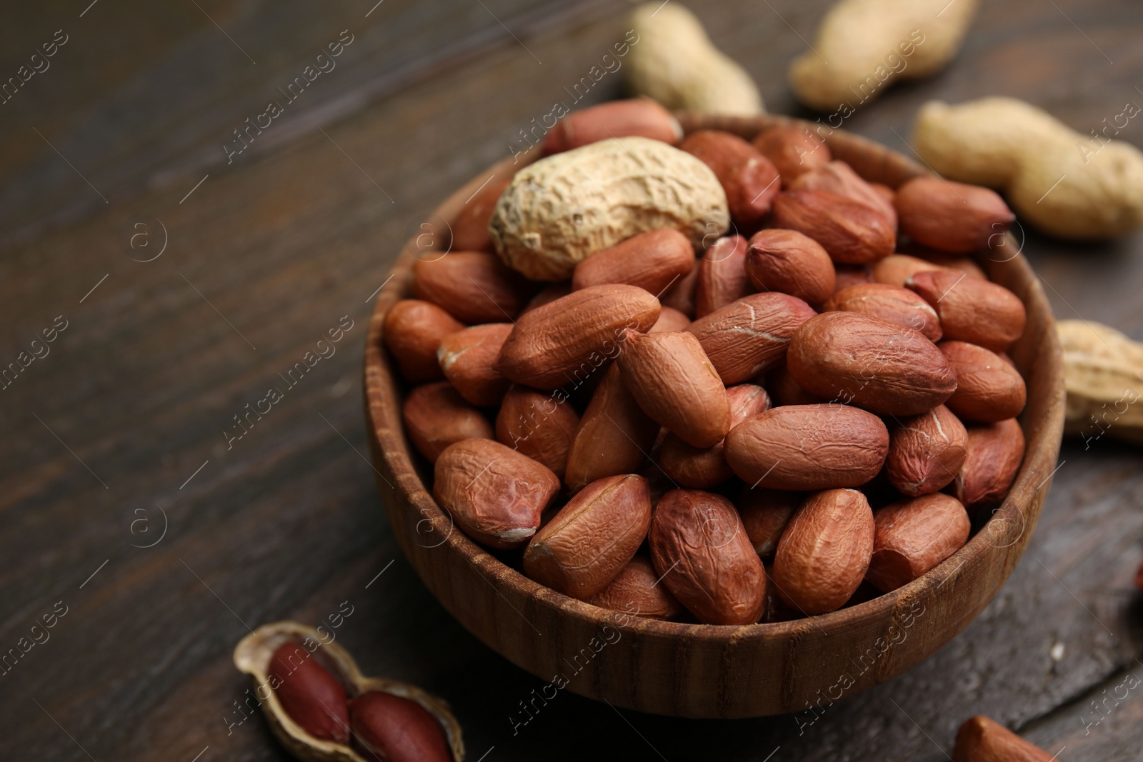 Photo of Fresh peanuts in bowl on wooden table, closeup. Space for text