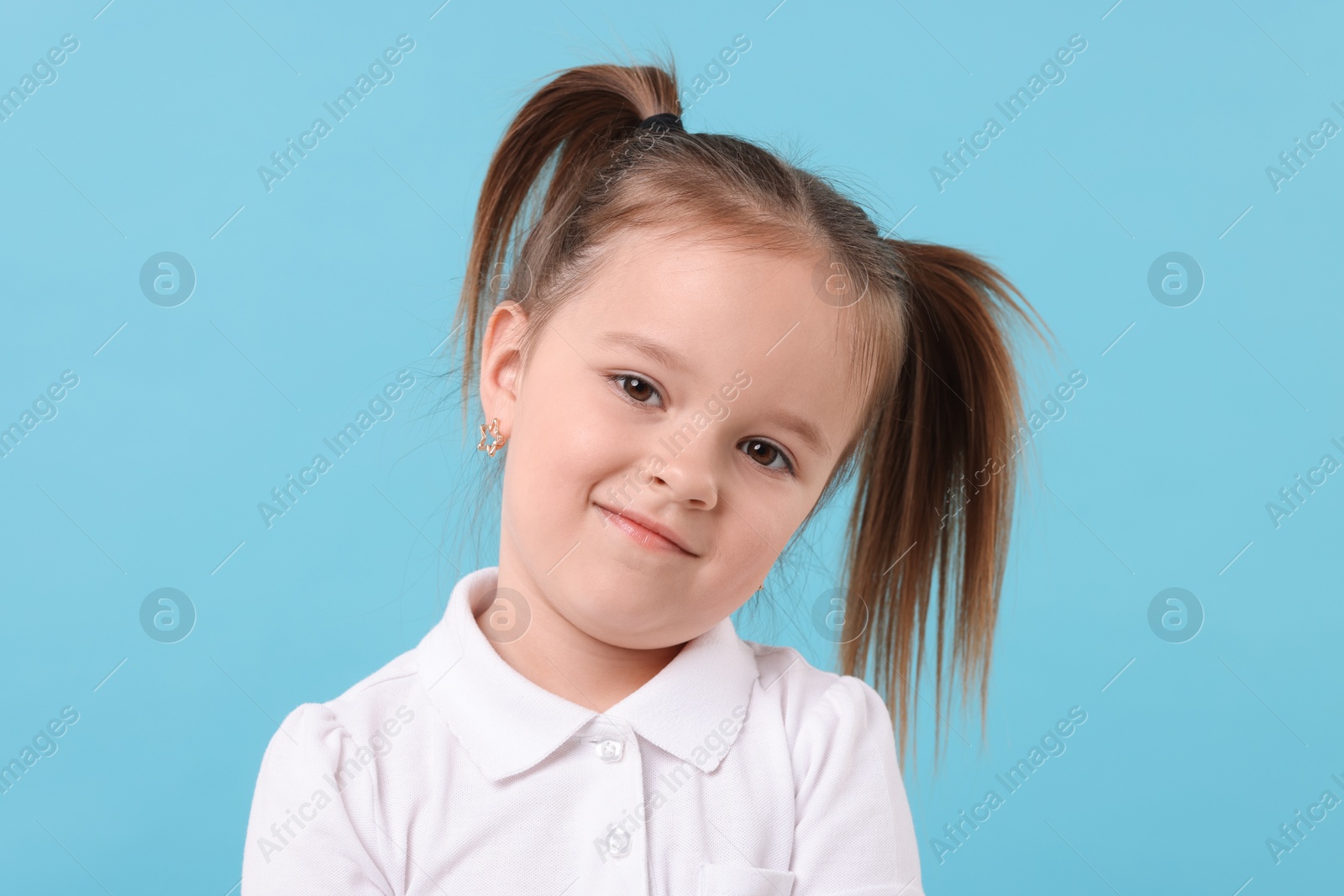 Photo of Portrait of cute little girl on light blue background