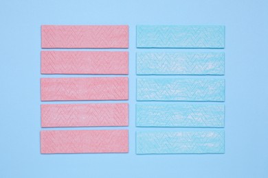 Sticks of tasty chewing gum on light blue background, flat lay