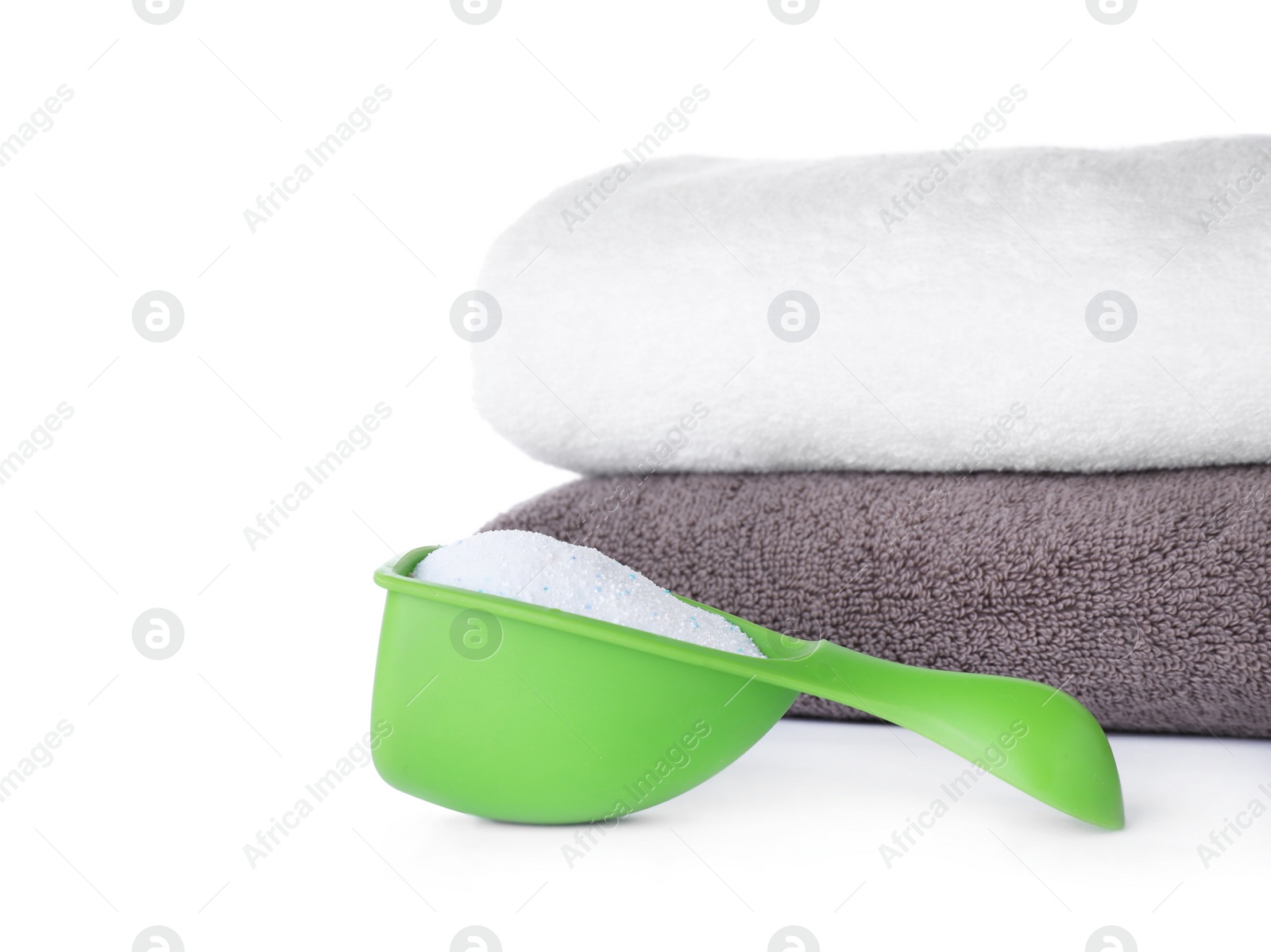 Photo of Laundry detergent in plastic measuring scoop and towels on white background