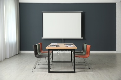 Photo of Modern meeting room interior with large table and projection screen