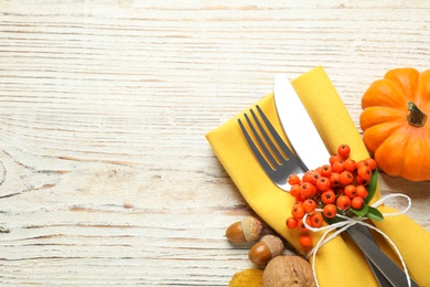 Photo of Top view of cutlery with napkin and autumn items on white wooden table, space for text. Thanksgiving Day