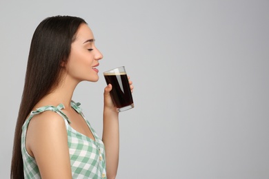 Photo of Beautiful woman with cold kvass on light grey background, space for text. Traditional Russian summer drink