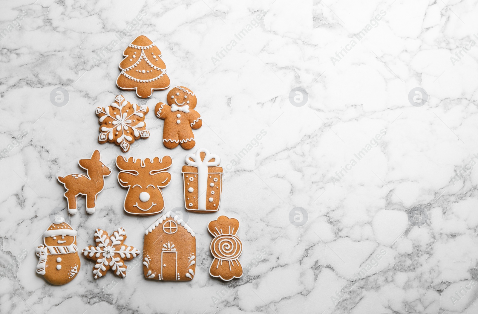 Photo of Christmas tree shape made of delicious gingerbread cookies on white marble table, flat lay. Space for text