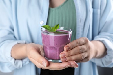 Photo of Woman with glass of tasty blueberry smoothie, closeup