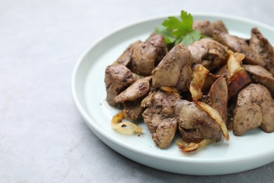 Tasty fried chicken liver with onion and parsley on grey table, closeup. Space for text