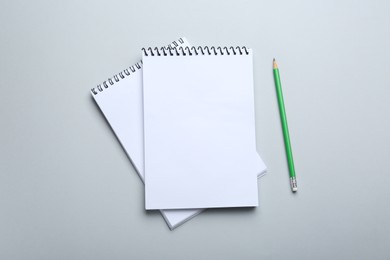 Photo of Notebooks and pencil on light grey background, top view