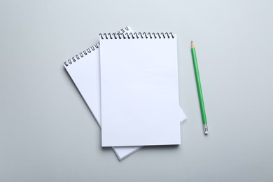 Notebooks and pencil on light grey background, top view