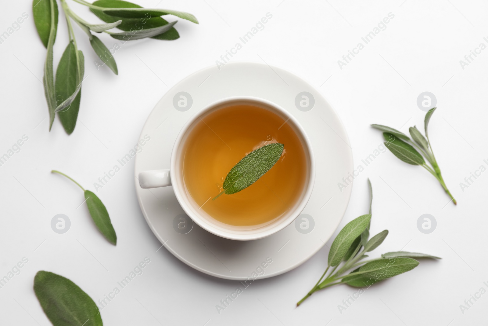 Photo of Cup of aromatic herbal tea with sage on white table, flat lay